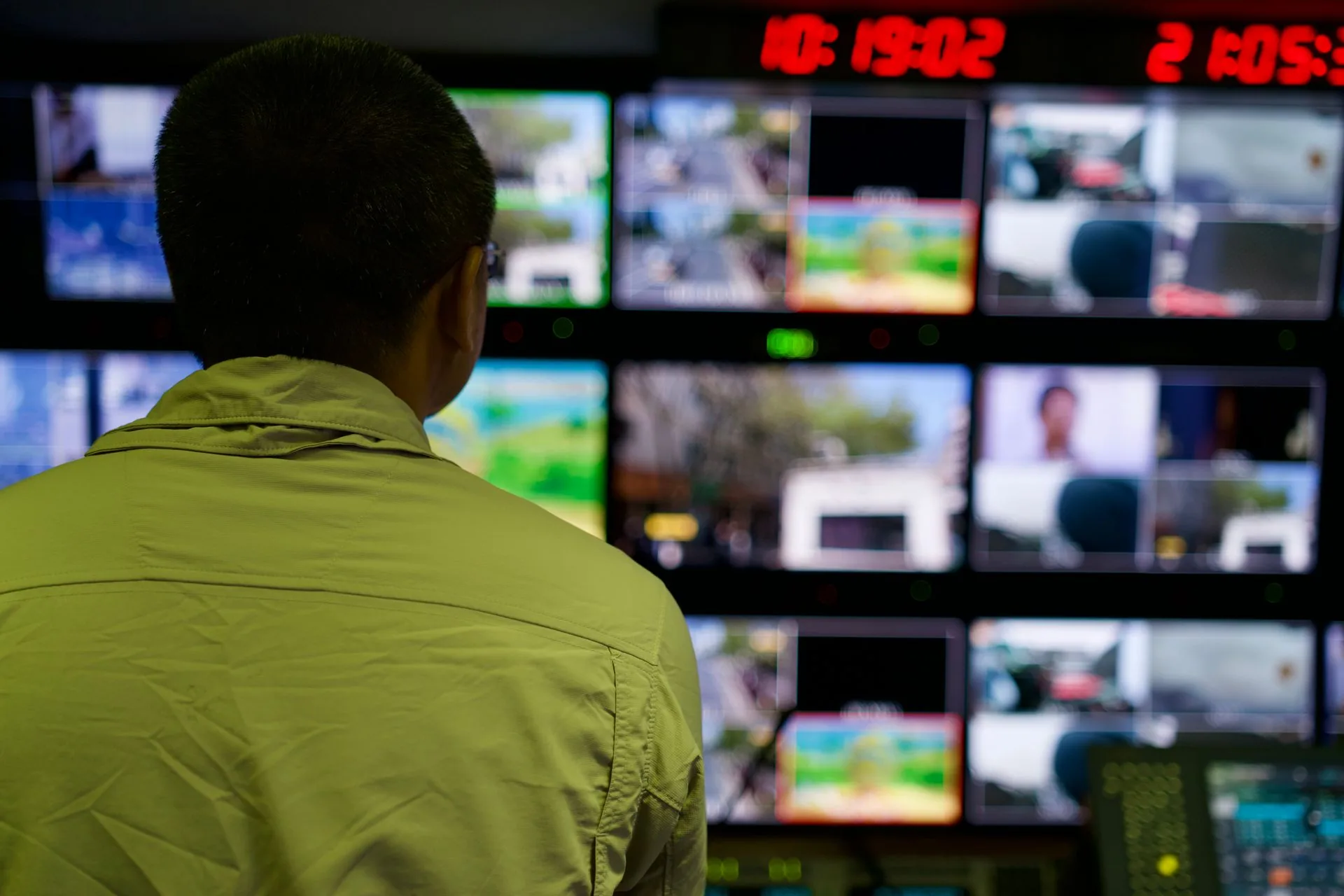 Engenheiro diante de um painel de monitores de transmissão ao vivo