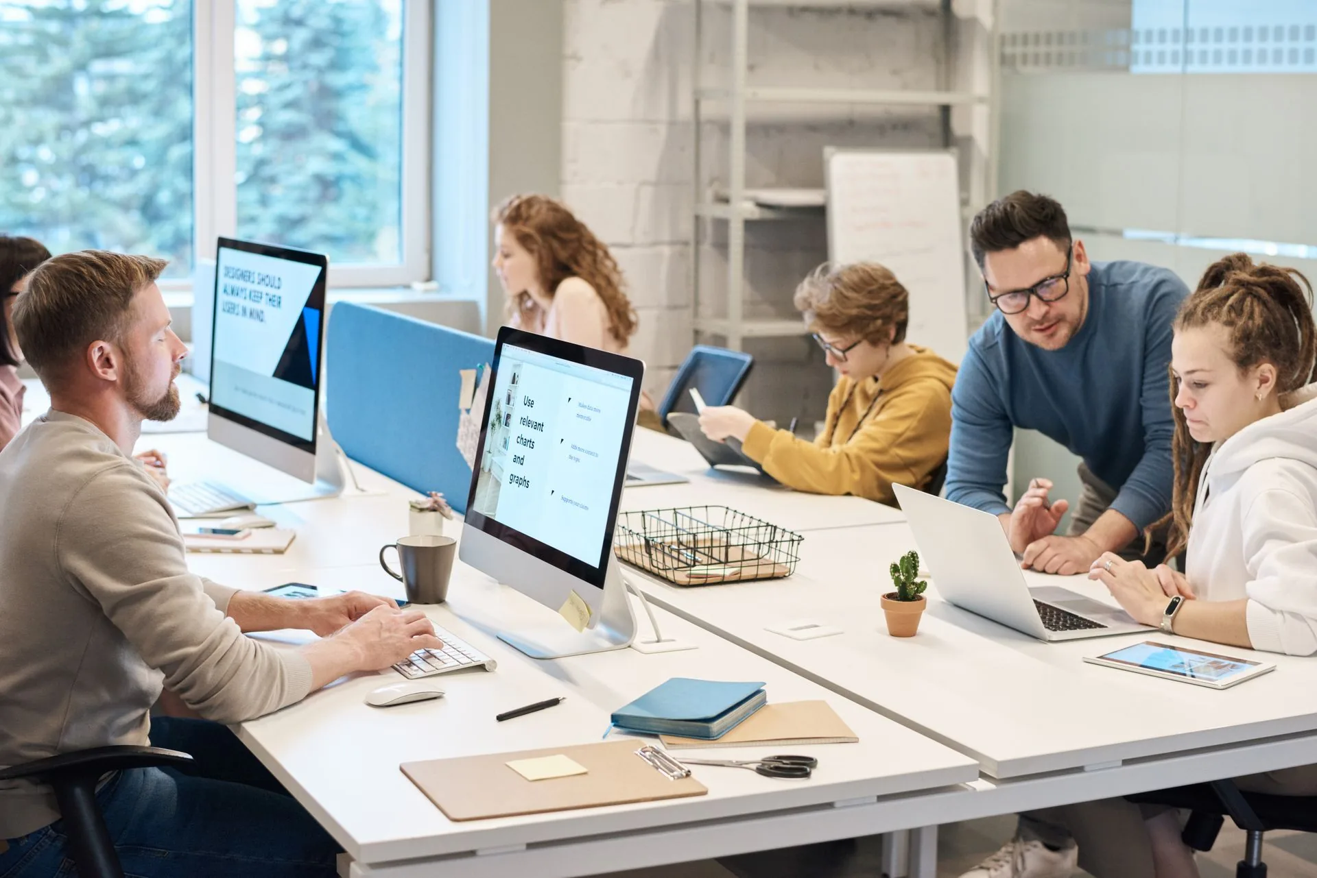 Equipe colaborando diante das telas em um escritório aberto