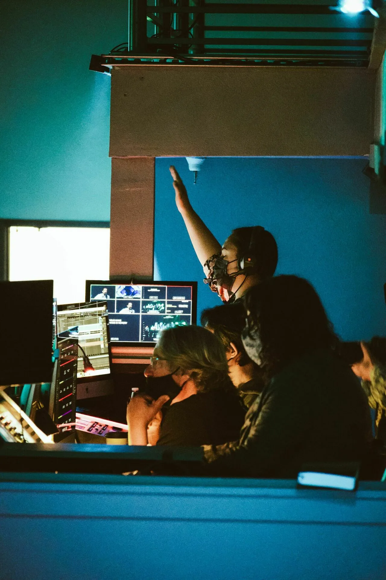 Broadcast control room crew at a wall of monitors and mixing desks during a live production