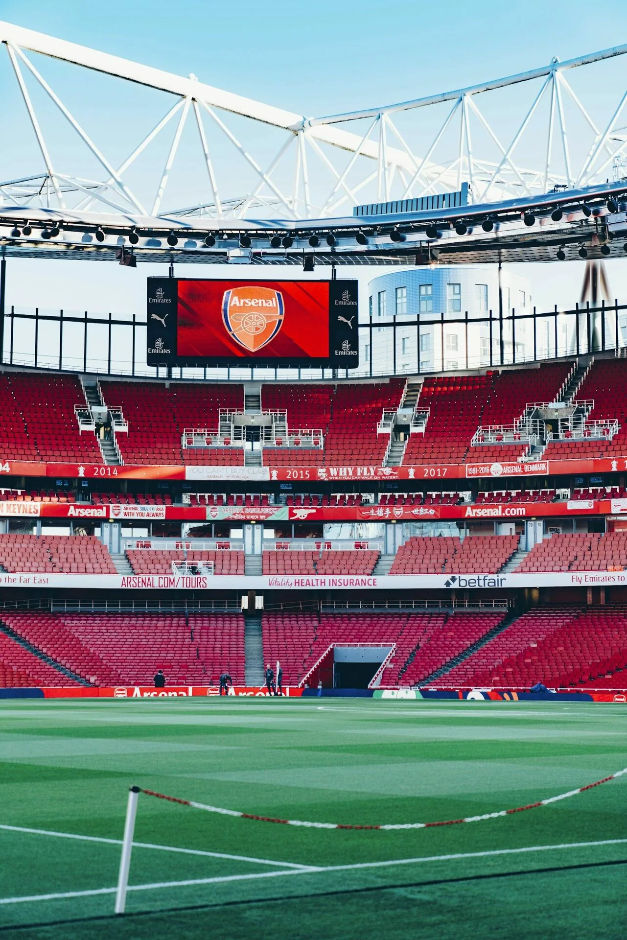 Empty football stadium with club branding on the big screen and sponsor boards ringing the red stands