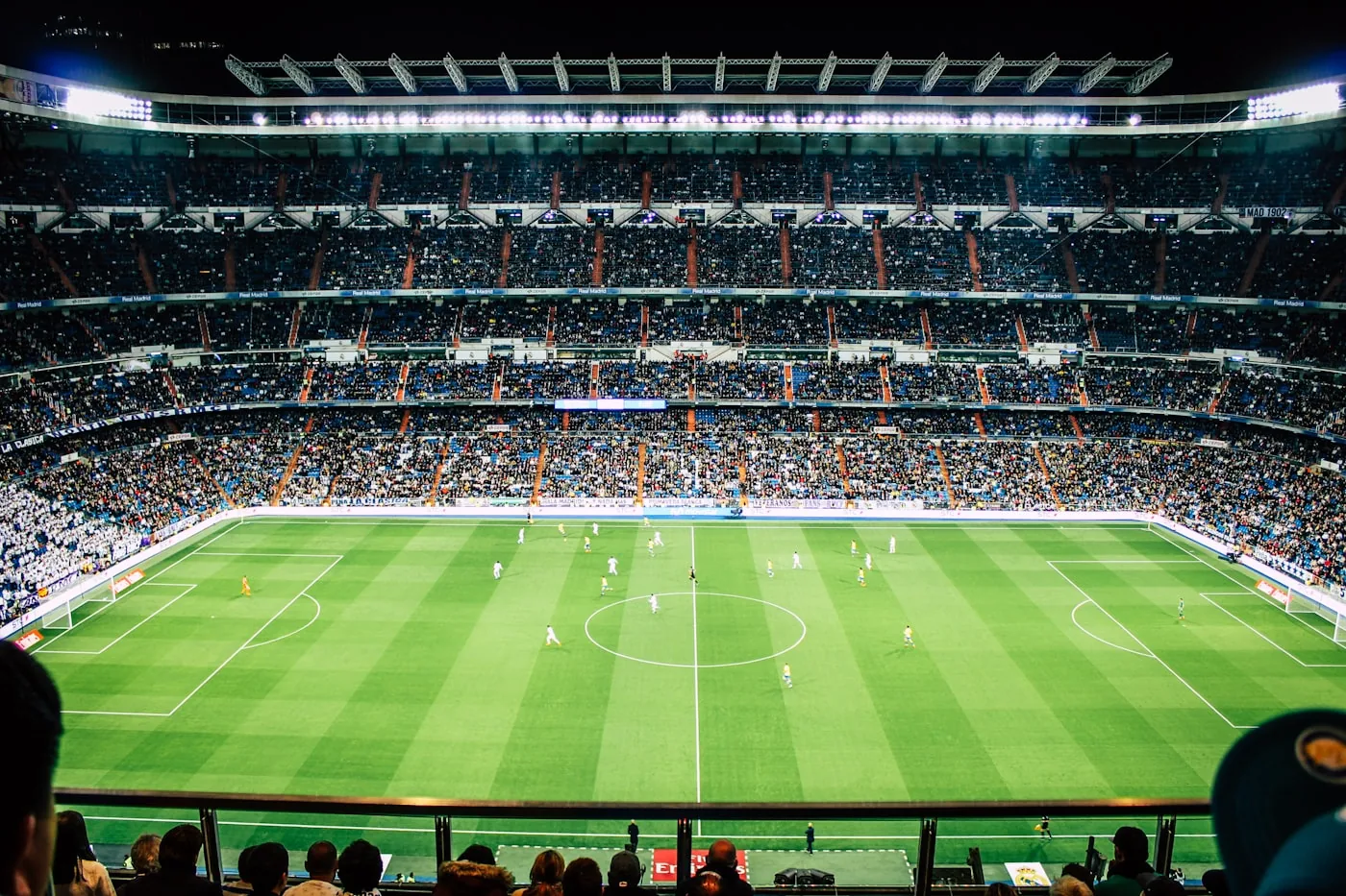 Interno di uno stadio illuminato con anelli di tribune, LED a bordo campo e il terreno di gioco durante un evento serale